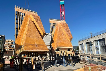 Nachtaufnahme einer STRABAG-Baustelle. Ein grosser Kran steht beleuchtet neben einem Wohnhaus unter dem klaren Nachthimmel.