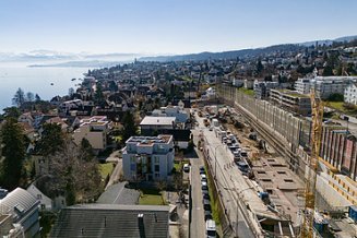 Rüschlikon Bahnhof Süd – STRABAG Tiefbau und Spezialtiefbau Baugrube in mitten in Rüschlikon im Hintergrund sieht man den Zürichsee und in weiter ferne die Alpen