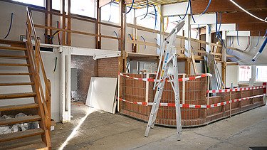 Innenausbau des Gmeindezentrumes. Viel helles Holz und rot weisse Absperrbänder.