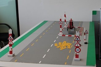Tischmodell einer Strasse mit Baustellenabsperrungen und Verkehrsschildern zur Schulung der Arbeitssicherheit.