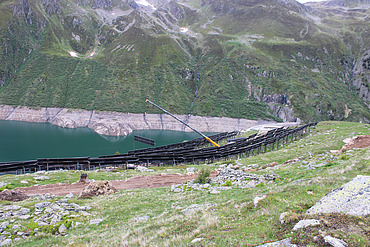 Kran zwischen vielen Solarpanels und im Hintergrund der Stausee Lai da Nalps