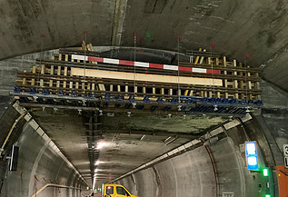 Nachtaufnahme einer STRABAG-Baustelle. Ein grosser Kran steht beleuchtet neben einem Wohnhaus unter dem klaren Nachthimmel.