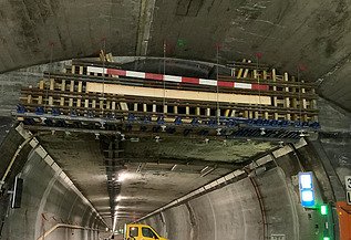 Nachtaufnahme einer STRABAG-Baustelle. Ein grosser Kran steht beleuchtet neben einem Wohnhaus unter dem klaren Nachthimmel.