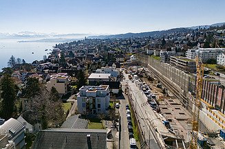 Rüschlikon Bahnhof Süd – STRABAG Tiefbau und Spezialtiefbau Baugrube in mitten in Rüschlikon im Hintergrund sieht man den Zürichsee und in weiter ferne die Alpen