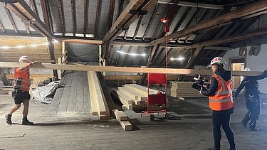 Zwei Zimmersleute am Balken tragen