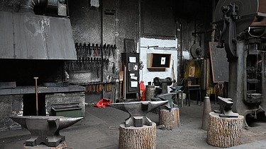 Inmitten der Halle befindet sich die «Zunf zur Schmiden» Sicht auf en alten Schmidofen und Ambosse