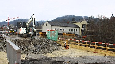 Weisser Bagger mit STRABAG Logo beim Abbruch der Wila Brücke