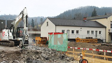 Weisser Bagger mit STRABAG Logo beim Abbruch der Wila Brücke
