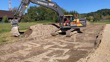 Baustelle zu frühem Zeitpunkt mit Bagger im Blick