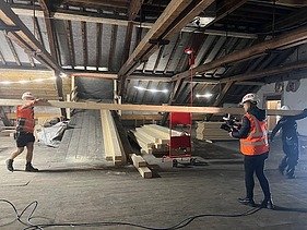 Zwei Zimmersleute am Balken tragen