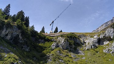 Blick aus grosser Distanz von unten auf die Baustelle mit prägnantem Kran