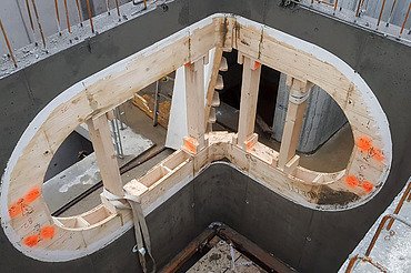 Nachtaufnahme einer STRABAG-Baustelle. Ein grosser Kran steht beleuchtet neben einem Wohnhaus unter dem klaren Nachthimmel.