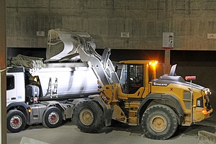 Gelber Bagger verlädt Kies in Lastwagen