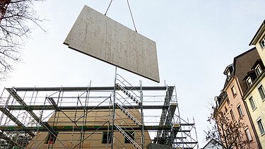 Ein Holzelement in der Luft durch einen Kran wird geliefert für die Dachkonstruktion.