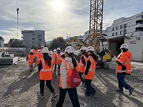 Gruppenbild der Gruppe im Hintergrund ist ein Mini-Bagger und Kran zu sehen