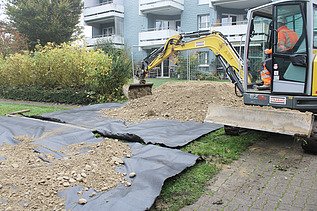 Gelber Bagger beim Verteilen des Erdmaterials