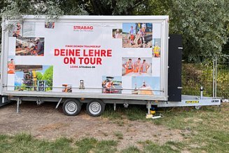 STRABAG Lehrlingsanhänger mit Bäumen im Hintergrund