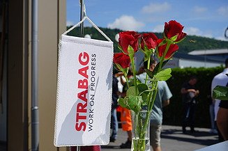 Vier STRABAG-Mitarbeiter vor Elektrobagger Vier Männer an einem Bagger stehend in STRABAG Kleidung