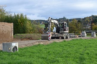 Bagger bei der Arbeit bei der Erschliessung des Baulandes, sichtbare Schächte