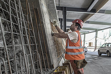 STRABAG - Mitarbeiter arbeitet unter einer Brücke an einer Stahlbewehrung im Bereich Verkehrsinfrastruktur.