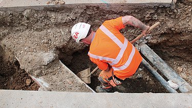 Foto von Arbeiten eines STRABAG Mitarbeitenden im Graben für Werkleitungen in Wangen mit