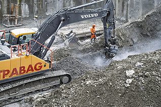 Bagger beim Abtrag von Felsgestein in der Baugrube