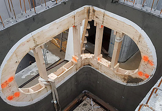 Nachtaufnahme einer STRABAG-Baustelle. Ein grosser Kran steht beleuchtet neben einem Wohnhaus unter dem klaren Nachthimmel.