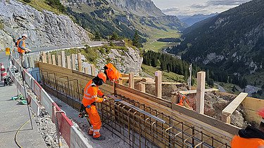 Verschiedene Mitarbeiter an der Arbeit an der Bewehrung mit Abschnitten, die unterschiedlich weit sind