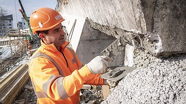 Maurer mit Burgerkelle am mauern