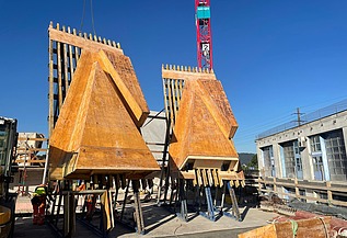 Nachtaufnahme einer STRABAG-Baustelle. Ein grosser Kran steht beleuchtet neben einem Wohnhaus unter dem klaren Nachthimmel.