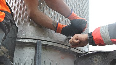 Nahaufnahme von zwei STRABAG Bauarbeitern, die an der Befestigung des Filterbrunnens arbeiten.