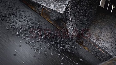Nahaufnahme von frischem Asphalt, der auf die Strasse fällt.