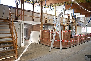 Innenausbau des Gmeindezentrumes. Viel helles Holz und rot weisse Absperrbänder.