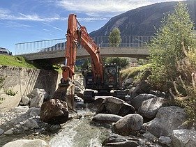 Arbeiten im Bach - STRABAG Ingenieurbau Bagger der STRABAG arbeitet direkt im Flussbett des Aclettbachs in Disentis unter einer Brücke.
