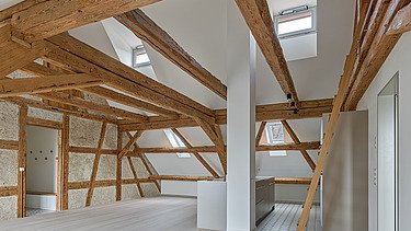 Foto von Dachgeschoss mit hellen Holzbalken und hellem Holzboden