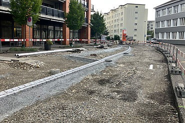 Nachtaufnahme einer STRABAG-Baustelle. Ein grosser Kran steht beleuchtet neben einem Wohnhaus unter dem klaren Nachthimmel.