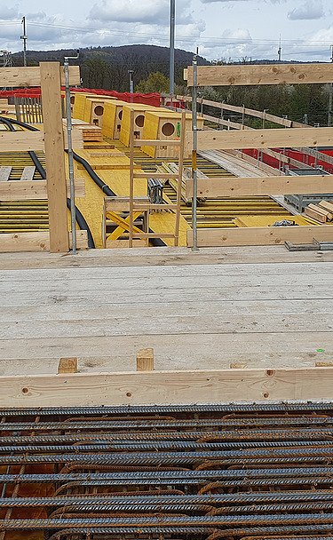 Nachtaufnahme einer STRABAG-Baustelle. Ein grosser Kran steht beleuchtet neben einem Wohnhaus unter dem klaren Nachthimmel.
