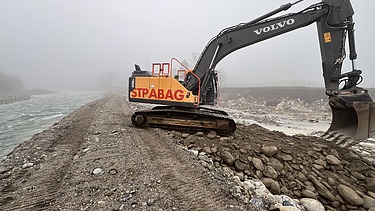 Foto von Arbeiten auf Sandbank der Reuss mit gelben STRABAG Bagger