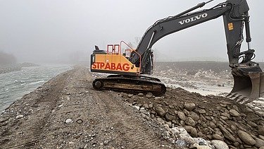 Foto von Arbeiten auf Sandbank der Reuss mit gelben STRABAG Bagger