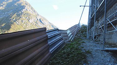 Ein Lawinenschutz und ein Gerüst auf einer Baustelle von STRABAG in den Schweizer Bergen.