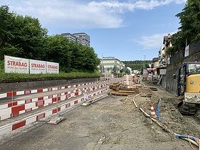 Die Baustelle an der Strasse mit Sturzsicherung, Bauzäunen und verschiedenen Baugeräten an einem bewölkten Tag.