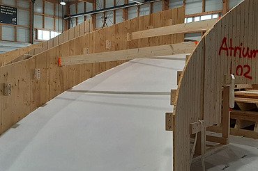 Nachtaufnahme einer STRABAG-Baustelle. Ein grosser Kran steht beleuchtet neben einem Wohnhaus unter dem klaren Nachthimmel.