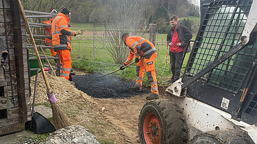 Zwei grosse Hebevorrichtungen auf einer STRABAG-Baustelle. Im Hintergrund sind Bauarbeiter:innen und ein Kran zu sehen.