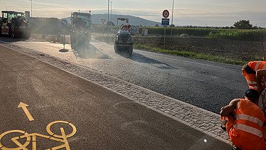 Asphaltieren auf der Baustelle mit Baugerät und Bauarbeiter im Blick