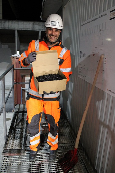 Mann mit Schachtel, in der heisser Asphalt drin ist.