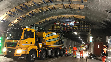Zwei grosse Hebevorrichtungen auf einer STRABAG-Baustelle. Im Hintergrund sind Bauarbeiter:innen und ein Kran zu sehen.