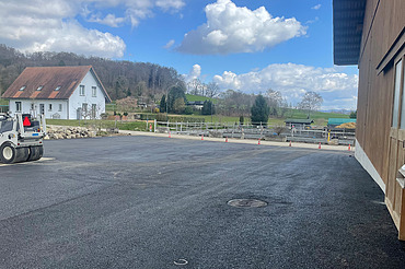 Nachtaufnahme einer STRABAG-Baustelle. Ein grosser Kran steht beleuchtet neben einem Wohnhaus unter dem klaren Nachthimmel.