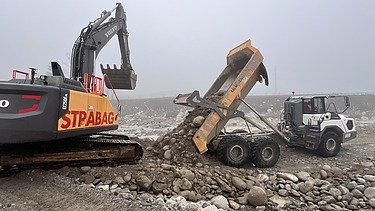 Foto von Arbeiten auf Sandbank der Reuss mit gelben STRABAG Bagger