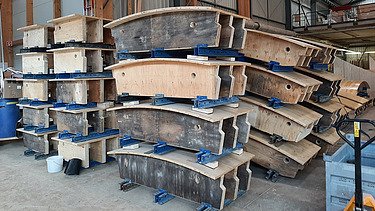  Ein Kran der STRABAG hebt nachts ein langes Brückenteil über Bahngleise. Die Baustelle ist hell erleuchtet.