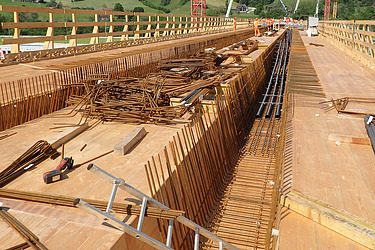 Holz-Betonschalung für den Bau einer Brücke. Zu sehen sind Bewehrungseisen und Holzelemente